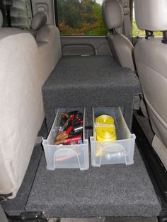 two plastic containers are sitting in the back seat of a car with other items inside