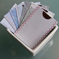 a white bowl filled with lots of different types of folded papers on top of a table