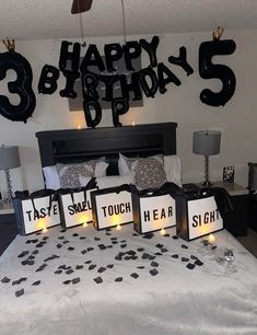 a bedroom decorated with black and white decorations, candles and birthday signs on the bed