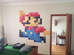 a room with a pool table, television and mario paper art on the wall