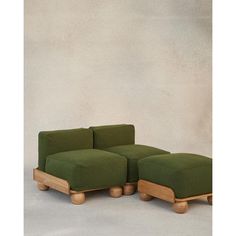 a green couch sitting on top of a white floor next to a wooden footstool