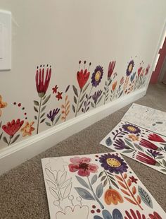 some flowers are painted on the wall next to two sheets of paper and a light switch