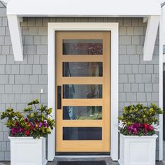 two planters with flowers in front of a yellow door