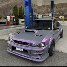 a purple car parked in front of a gas station