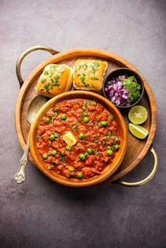 a wooden bowl filled with food next to some bread and coleslaw on a plate