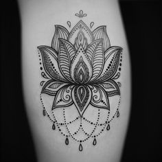 a black and white photo of a flower tattoo on the thigh, with water drops