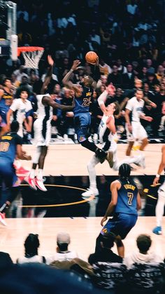 a basketball player jumping up into the air to dunk a ball in front of an audience