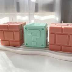 three lego blocks sitting on top of a white counter next to each other, one with a question mark in the middle