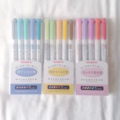 four pens are lined up in the same row on a white sheet with japanese writing