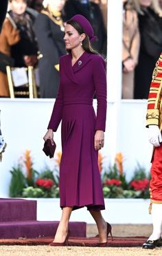 the royal couple are dressed in uniform and walking next to each other at an event