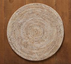 a round woven placemat sitting on top of a wooden table