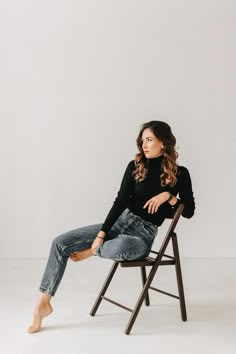 a woman sitting in a chair with her legs crossed and looking off to the side