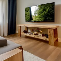 a flat screen tv sitting on top of a wooden stand in a living room next to a window