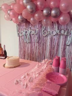 a pink table topped with a cake and balloons