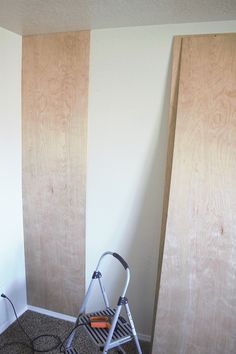 a small folding chair sitting in front of two plywood boards that are being built into the wall