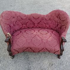 a pink couch sitting on top of a cement floor