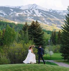 a bride and groom dancing in the mountains