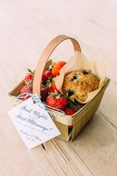 a basket filled with strawberries and muffins on top of a wooden table