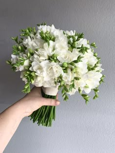 a hand holding a bouquet of white flowers