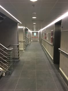 an empty hallway with stairs and railings leading up to the exit door on either side