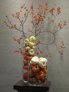 an arrangement of pumpkins and gourds in a vase