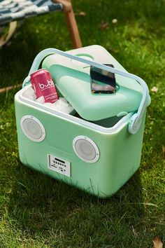 an ice chest is sitting in the grass next to a blanket and cell phone on it