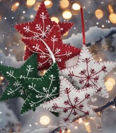 three christmas ornaments hanging from a tree with snow flakes on it and lights in the background