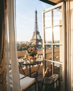 an open window overlooking the eiffel tower in paris, with a table set for two