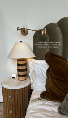 a bed with a lamp on top of it next to a night stand and side table