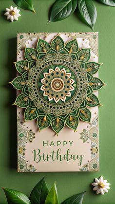 a green and white birthday card with an intricate design on the front, surrounded by greenery