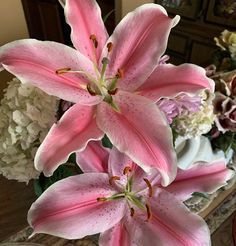 some pink flowers are in a vase on a table next to other white and pink flowers