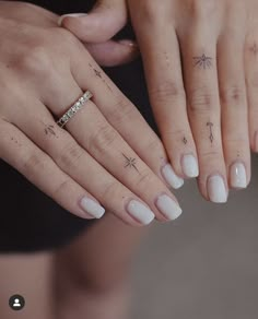 two hands with white manies holding each other's fingers and tattoos on them