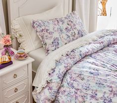 a white bed topped with lots of pillows next to a night stand and nightstands