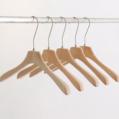 four wooden hangers are hanging on a white rail