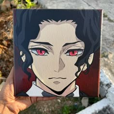 a hand holding up a painting of a man with red eyes and long black hair