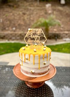 a yellow and white birthday cake sitting on top of a wooden table next to a park