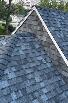 the top of a roof with a bird sitting on it's shingles and trees in the background