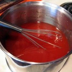 a metal bowl filled with red liquid on top of a stove