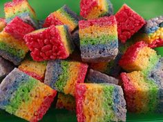 a pile of rainbow cake treats sitting on top of a green plate