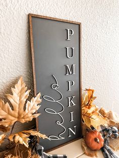 a sign that says pumpkin on it next to fall leaves and acorns in front of a white wall