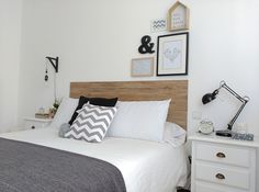 a bed with white sheets and pillows in a bedroom next to a wall mounted clock