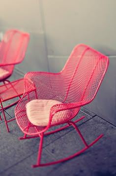 three red chairs sitting next to each other on a sidewalk in front of a building