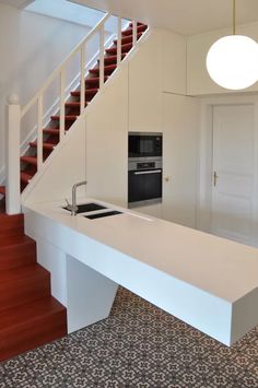 a kitchen with an island counter and stairs leading up to the second floor in this modern home