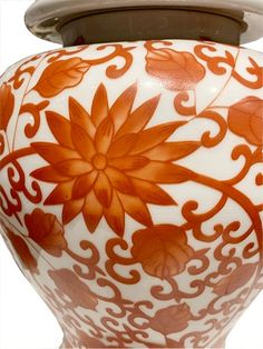 an orange and white vase sitting on top of a table