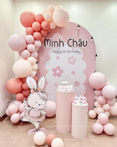 a pink and white birthday party with balloons, bunnies, cake and decorations on the floor