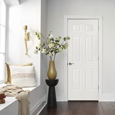 a vase filled with flowers sitting on top of a wooden floor next to a white door