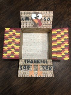 a turkey made out of cardboard sitting on top of a wooden floor next to a sign that says thank you