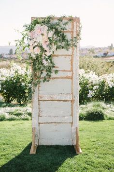 an old door is decorated with flowers and greenery for a rustic outdoor wedding ceremony