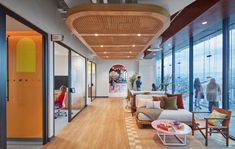 an office with lots of windows and people standing in the room looking out at the city