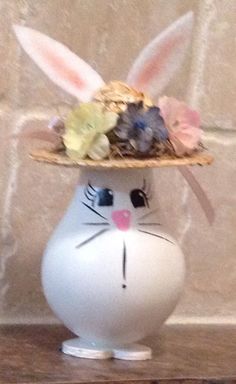 a white vase with a bunny face wearing a straw hat on top of it's head